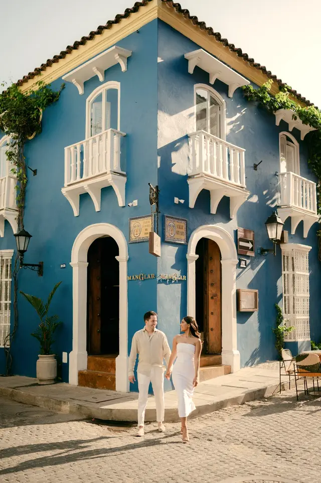 Couple in front of a blue colonial house with white balconies