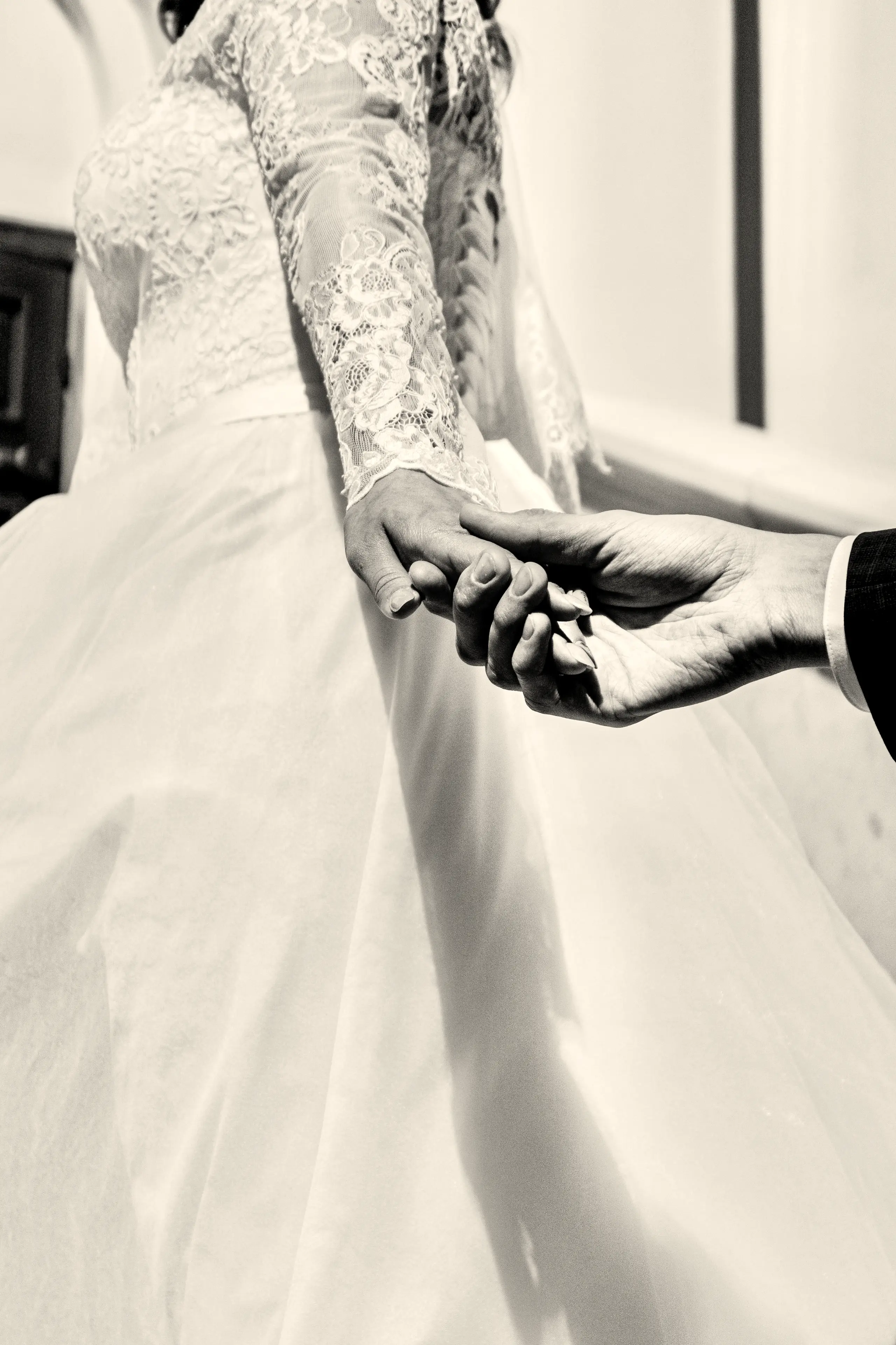 The couple's hands joined over the lace of the wedding dress, in black and white