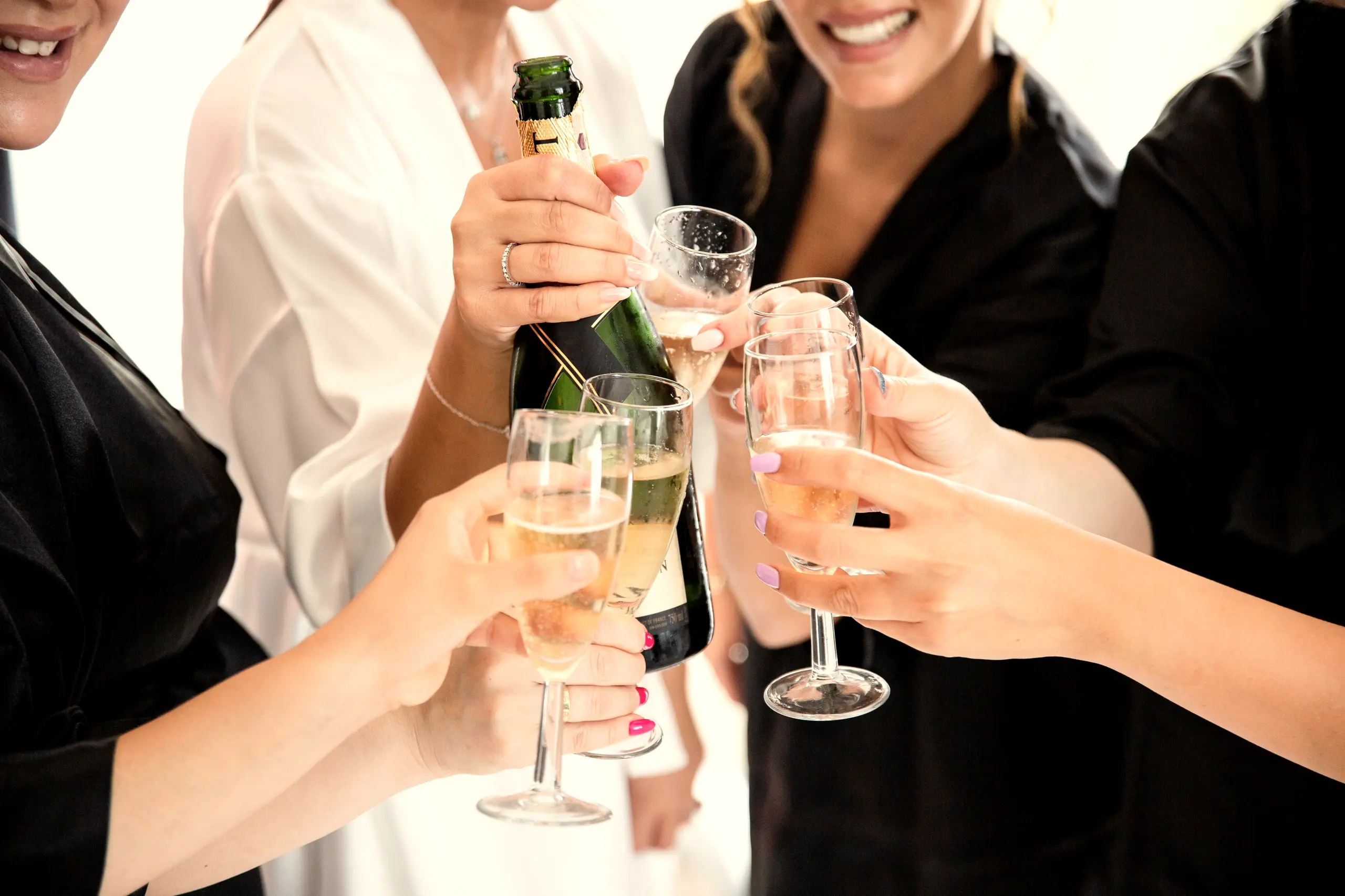 Champagne toast among women dressed in white and black