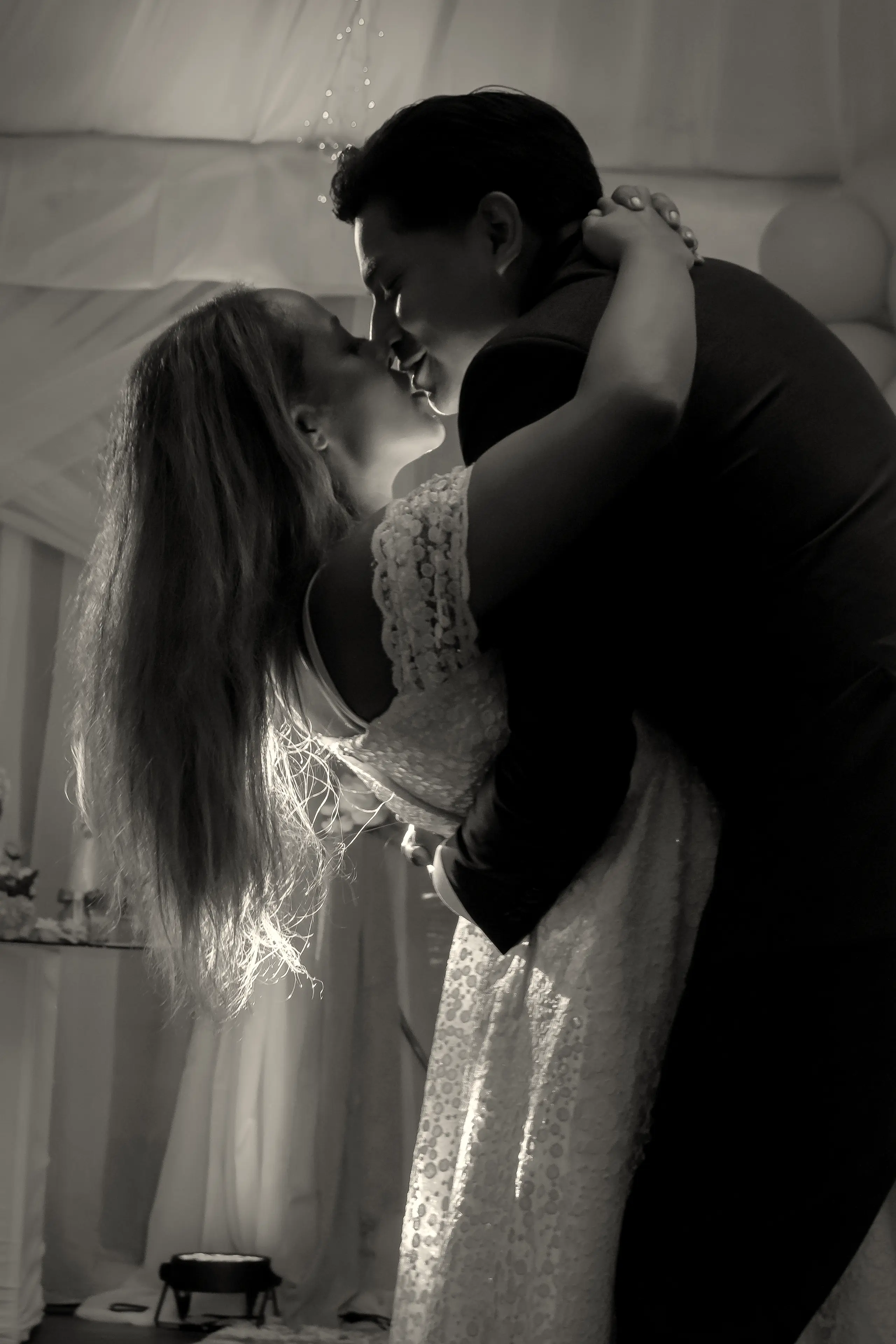 Couple embracing in black and white, her veil over her shoulder