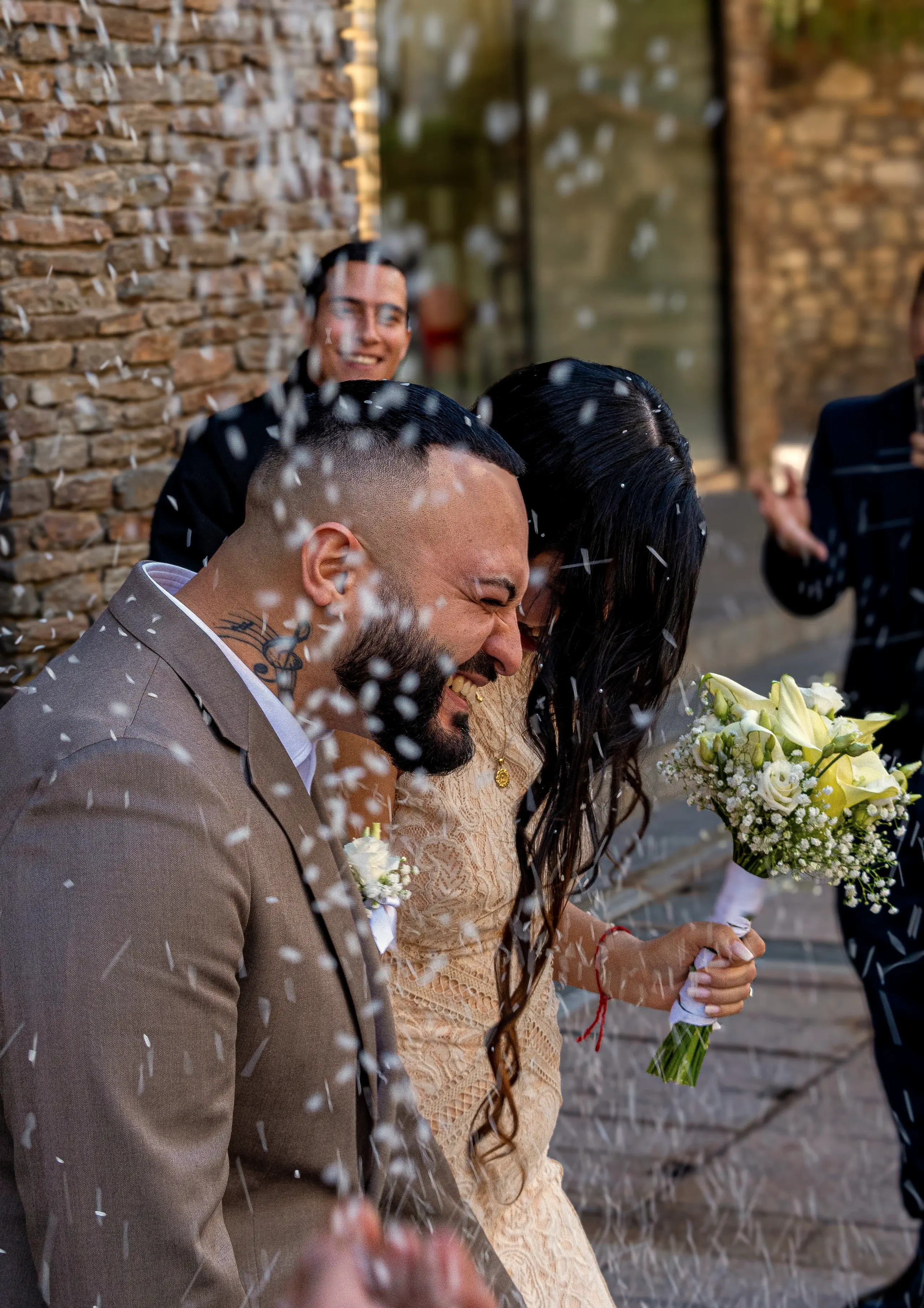 Newlyweds laughing under a shower of confetti as they leave the ceremony