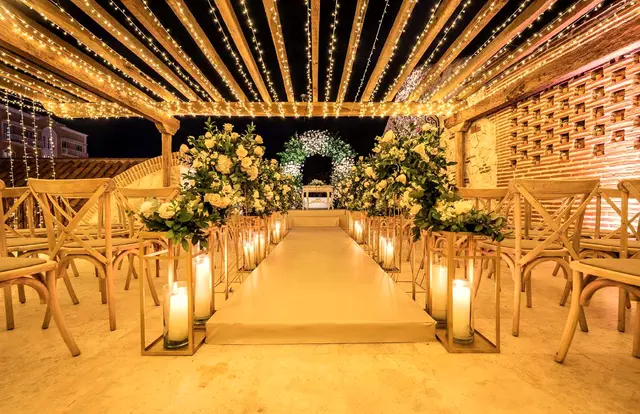 Ceremony aisle with candles, white flowers and a canopy of lights at night