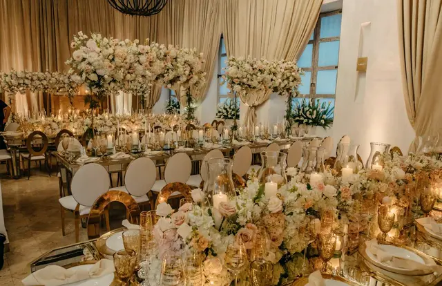 Banquet table with white floral centerpieces, gold glassware and candles