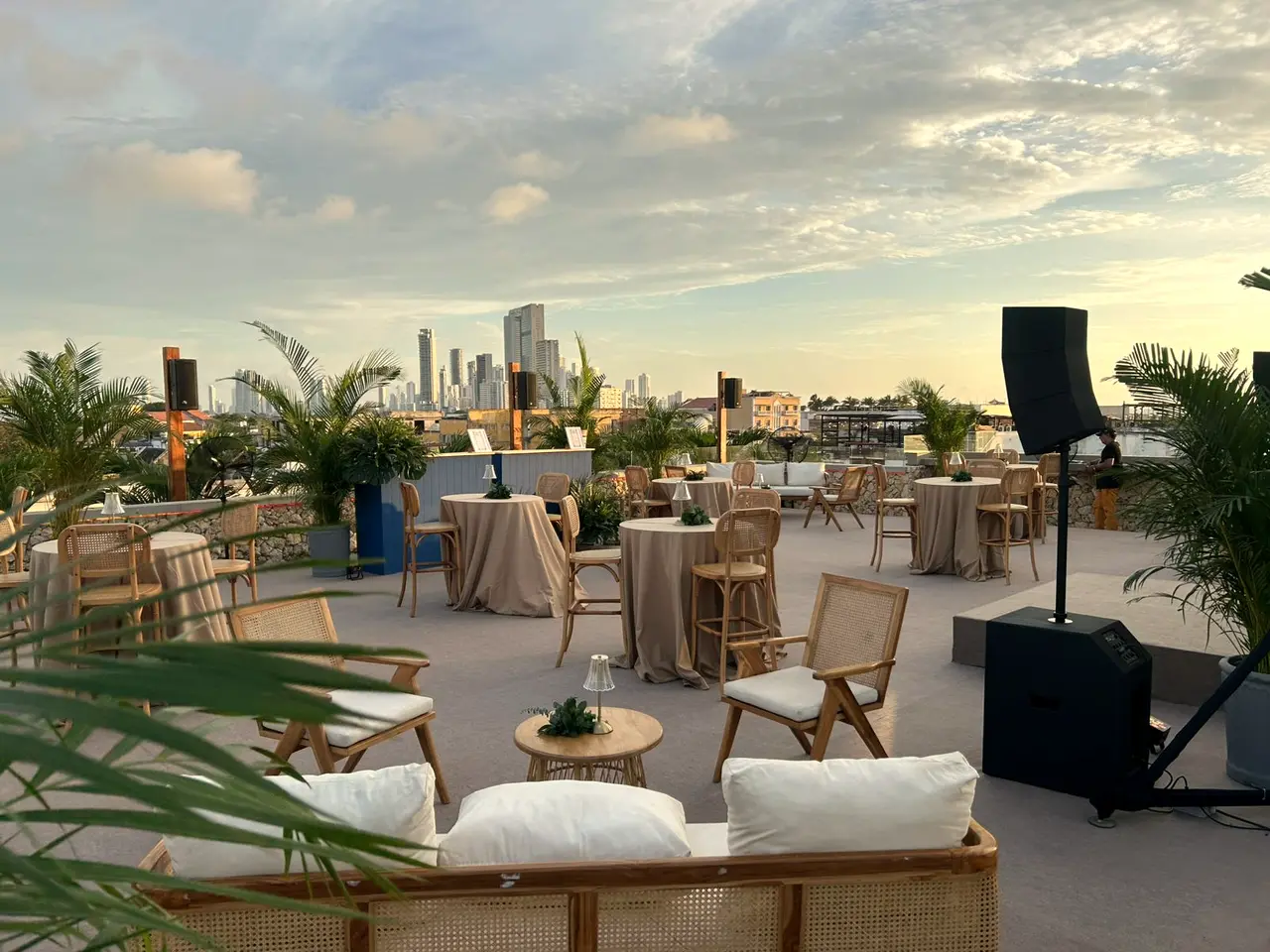 Terrace at sunset with rattan chairs, tables and the city skyline