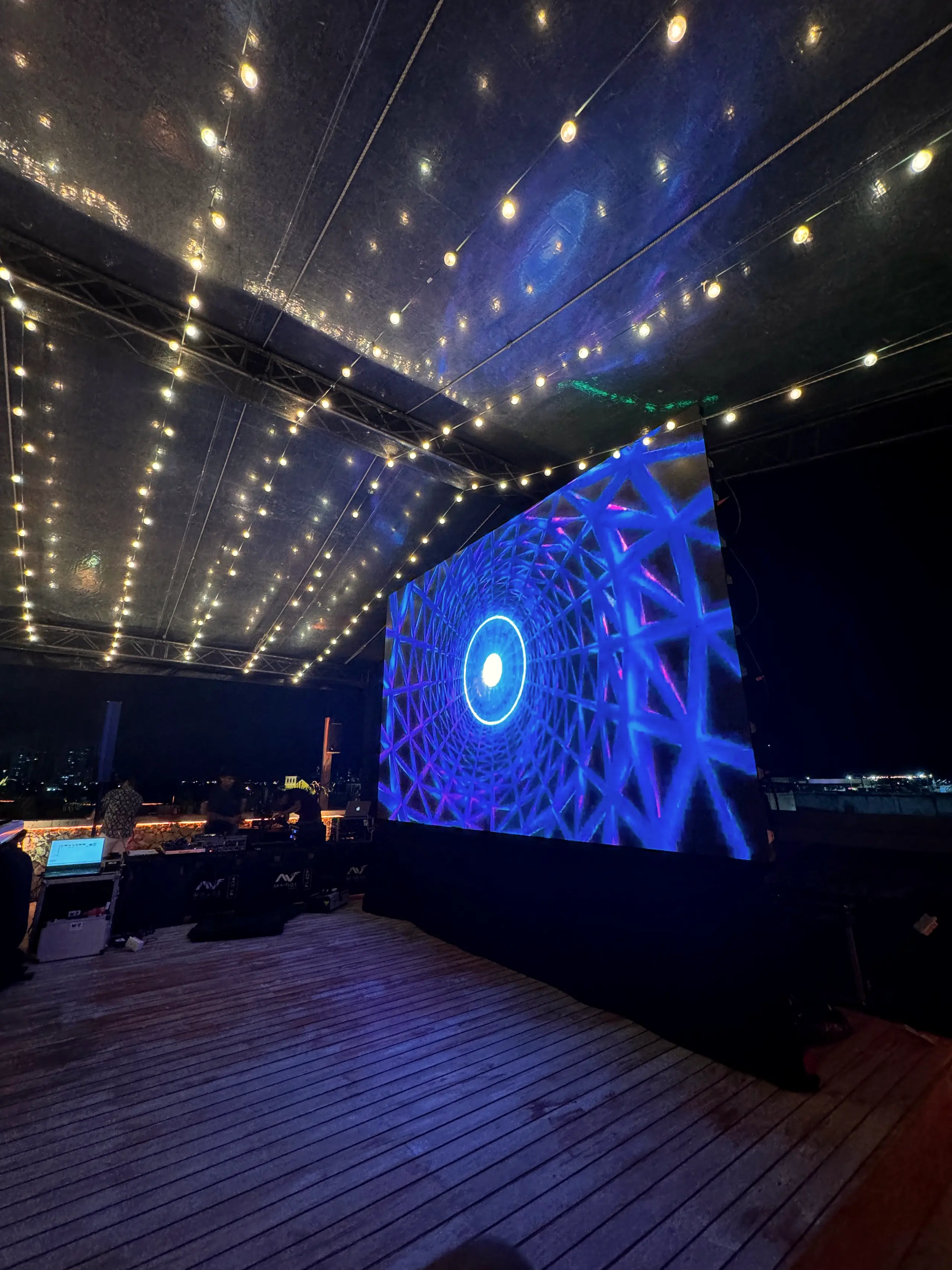 Blue screen under a canopy of warm string lights on a terrace