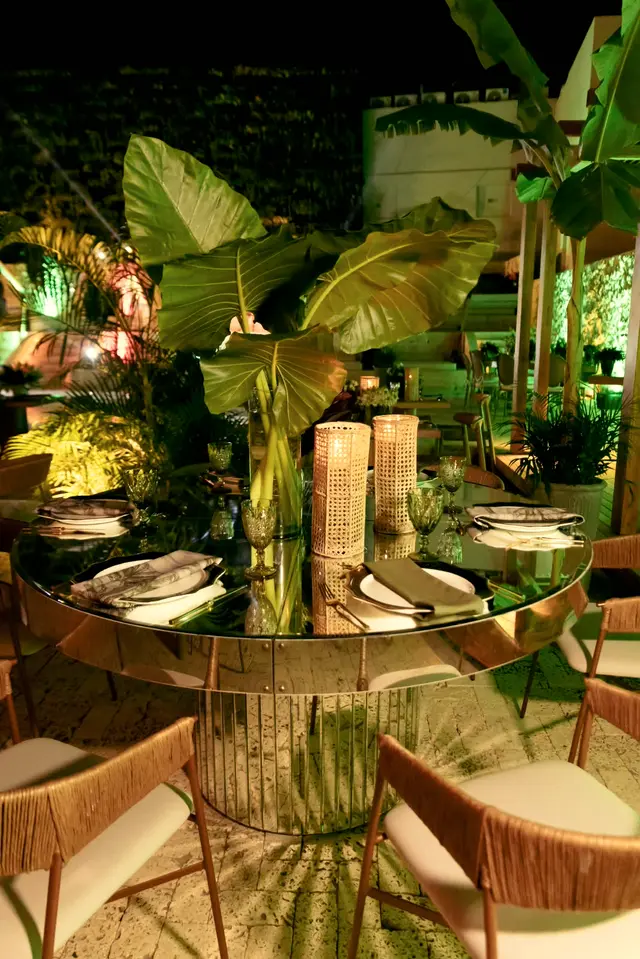 Table centerpiece of banana leaves and candles on a mirrored table