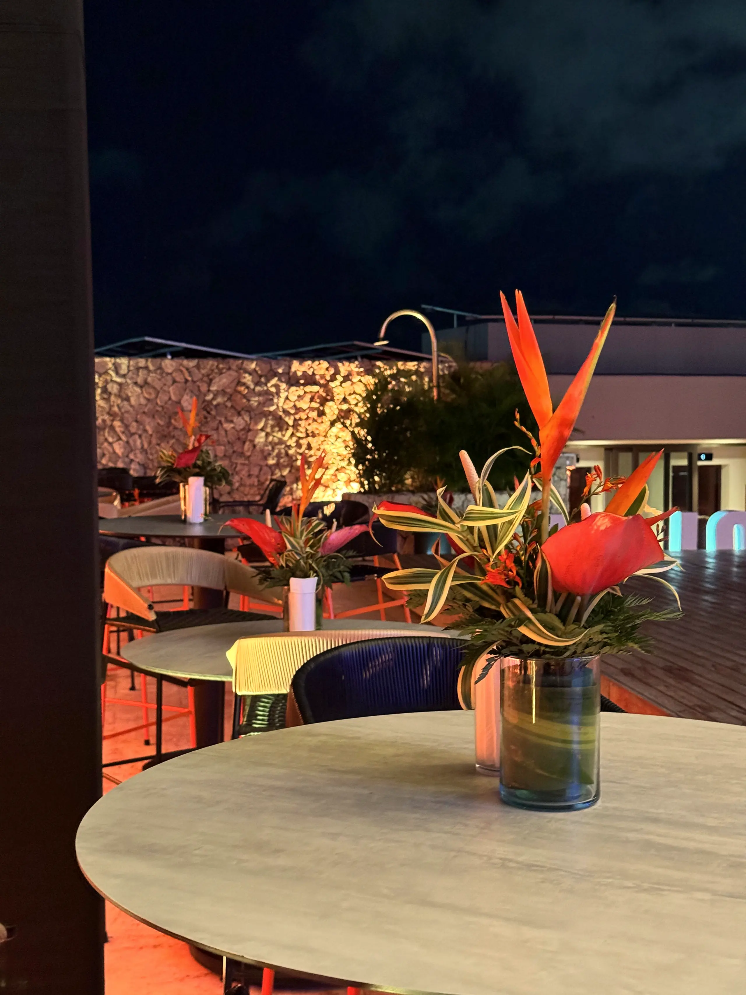 Wooden table with a heliconia and bird-of-paradise arrangement at night
