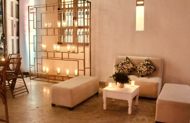 Rincón con sofás color crema y velas frente a una celosía dorada
