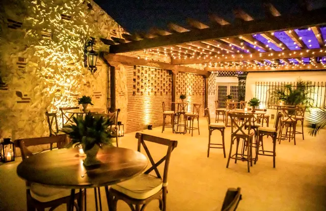Terraza con pérgola de madera y mesas altas de cóctel de noche