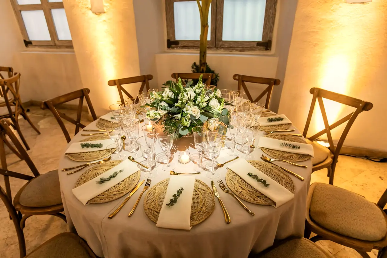 Round table set with white flowers in a stone room with warm light