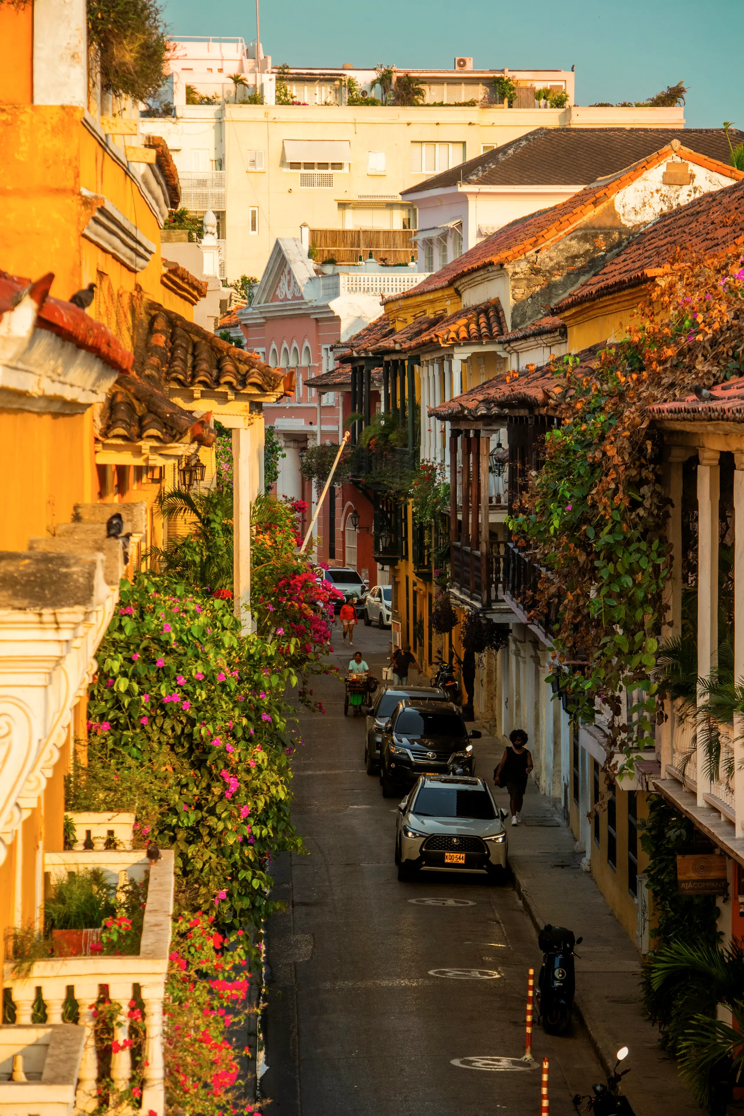 Calle del centro histórico al atardecer con balcones cubiertos de flores