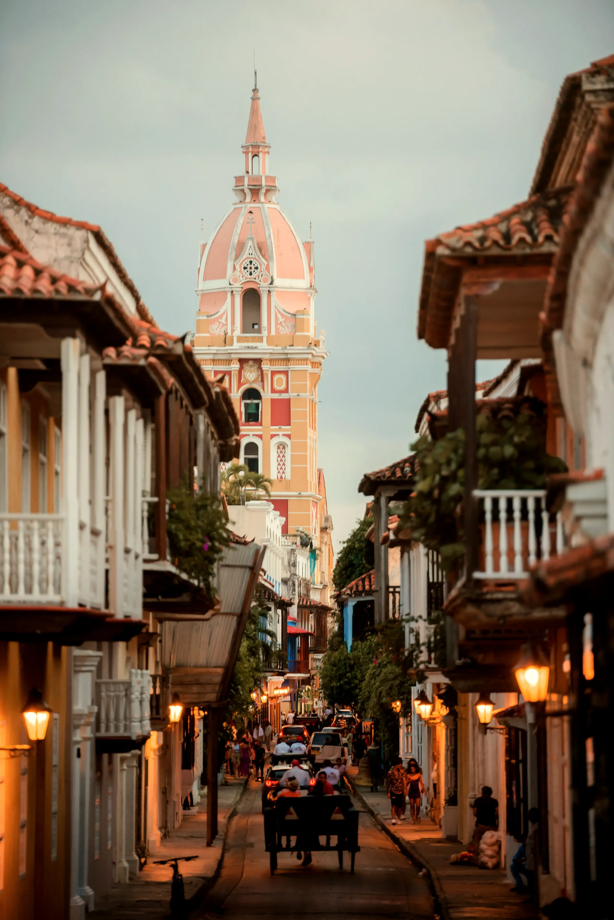 Pink church tower at the end of a street with lights at dusk