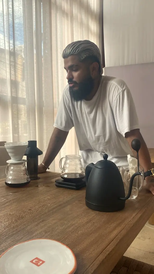 Man preparing filter coffee at a wooden table