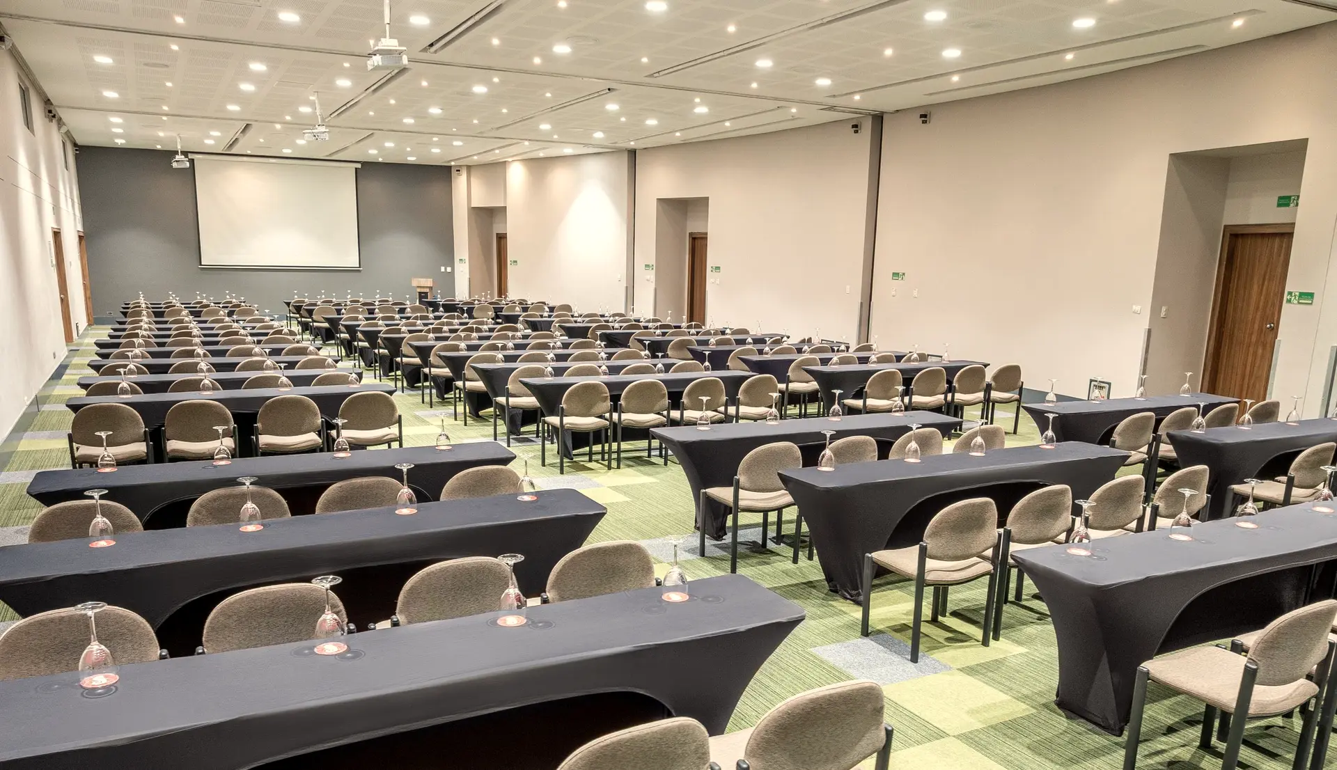 Salón de congresos en formato escuela con pantalla al fondo