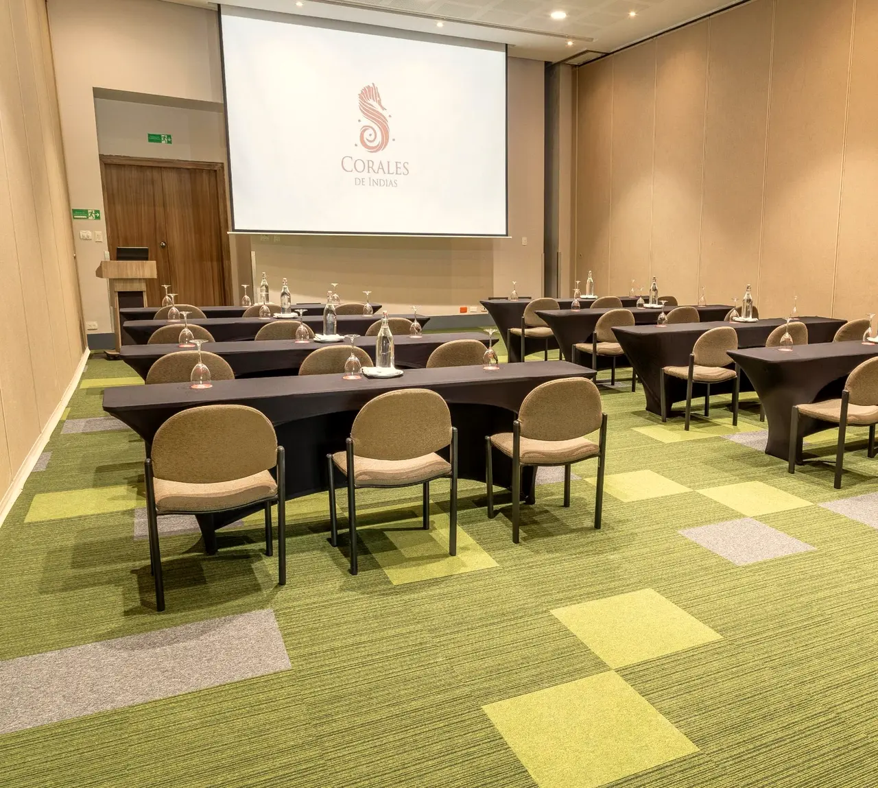 Salón de capacitación con mesas largas y pantalla