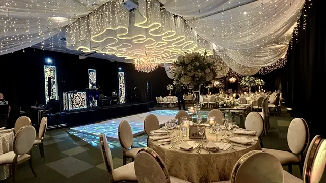 Salón de gala con pista de baile iluminada, mesas redondas y techo de luces