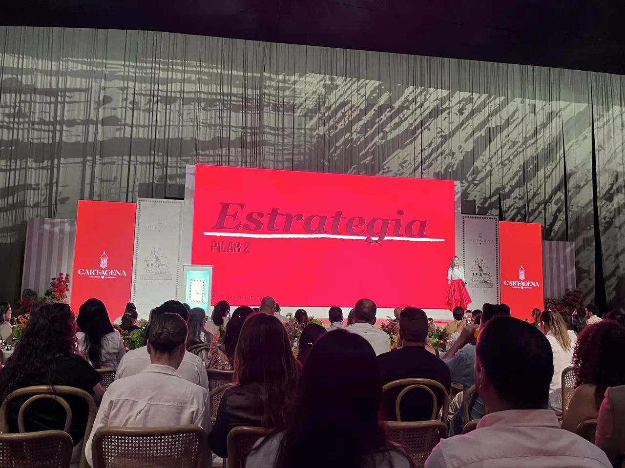 Convention in a theater with a red screen and audience