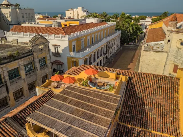 Vista elevada de la azotea con sombrillas naranjas y los tejados del centro histórico