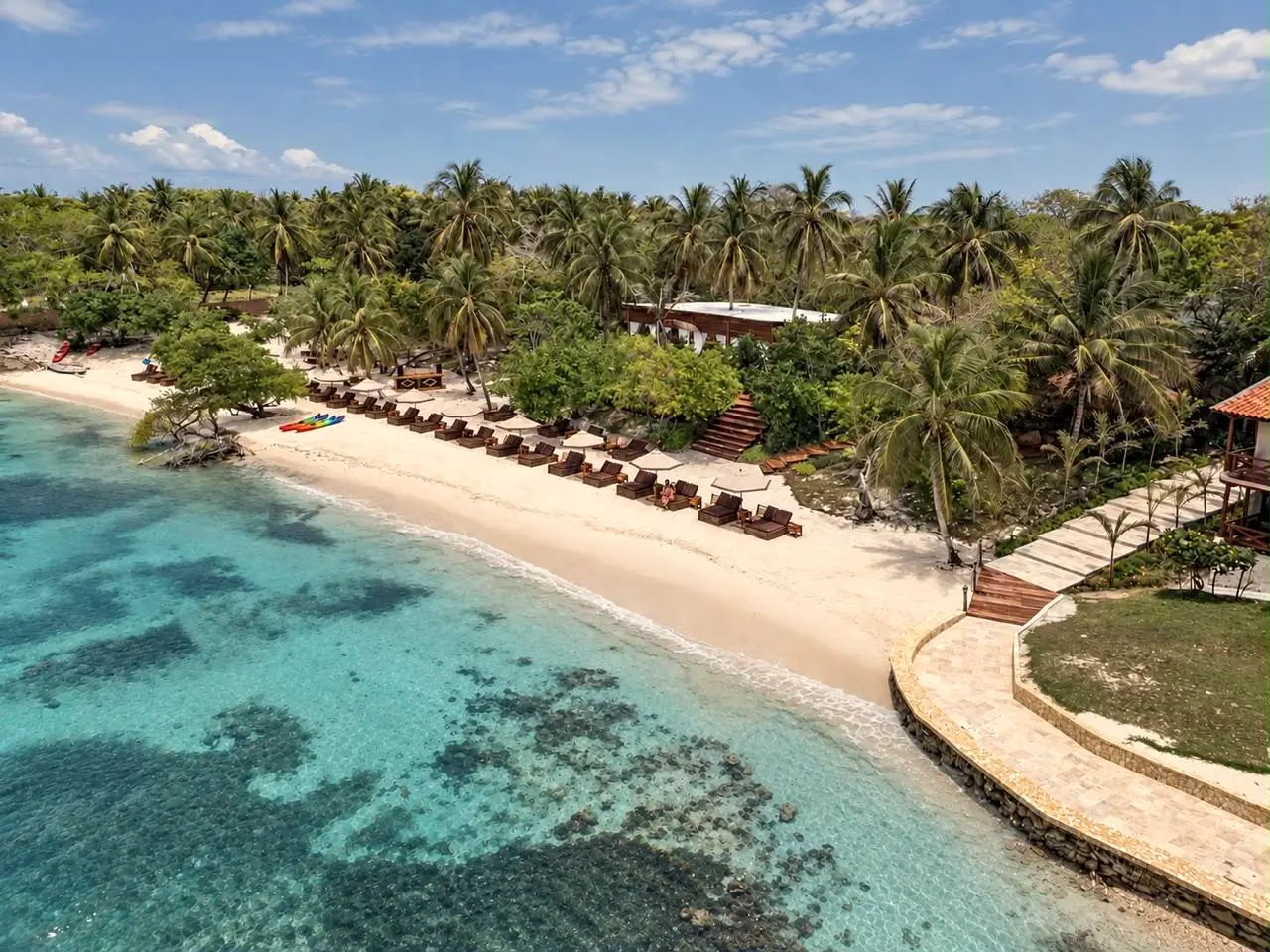 Aerial view of a pale-sand beach with turquoise water and palms
