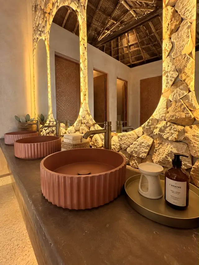 Bathroom with a carved stone mirror and a pink ceramic basin