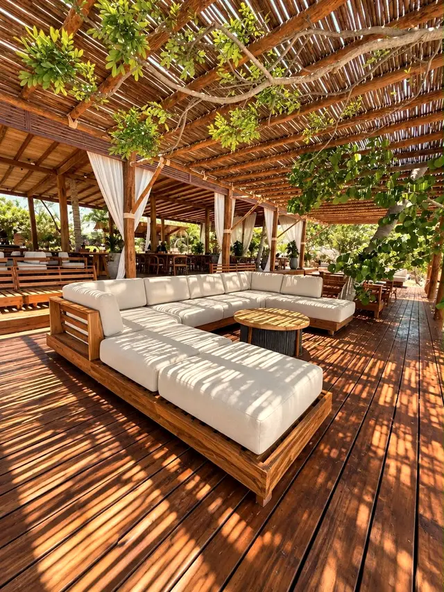 Wooden deck with a white sofa and cane roof among trees by the beach