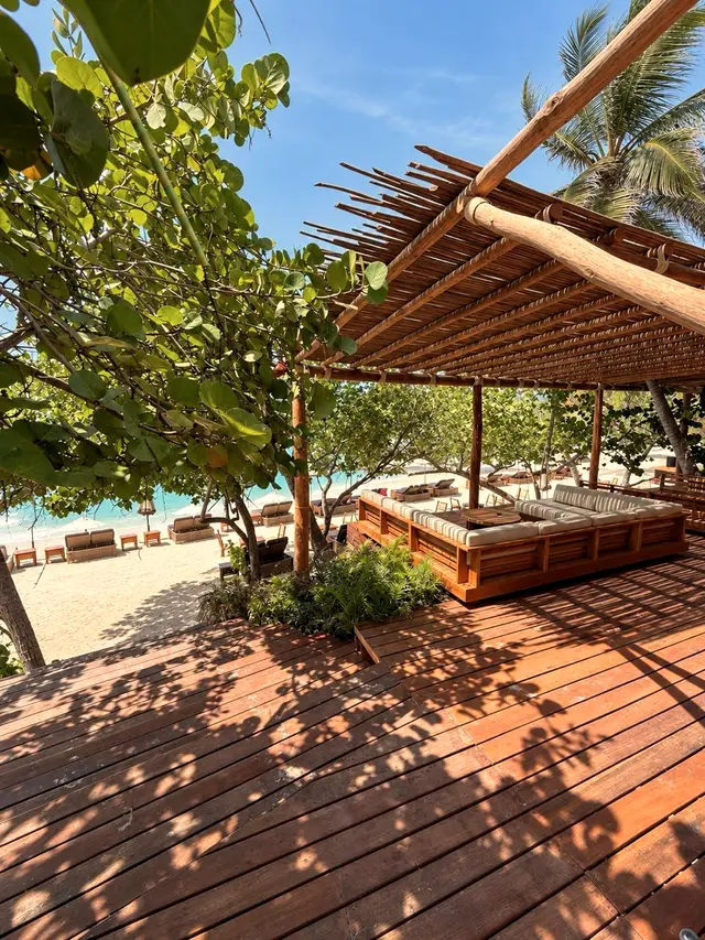 Wooden deck with a cane pergola and a beach view