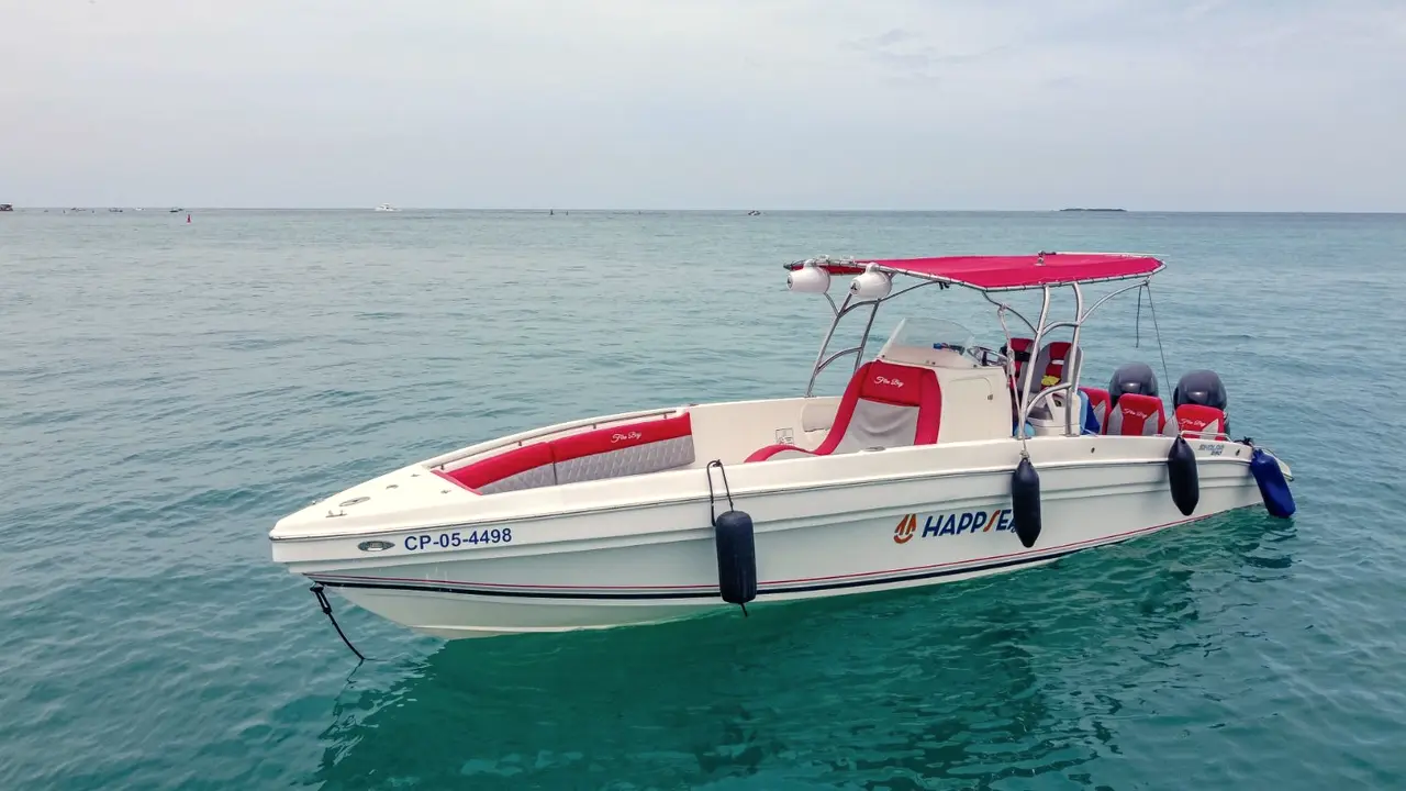 Lancha blanca con toldo rojo anclada en aguas turquesa