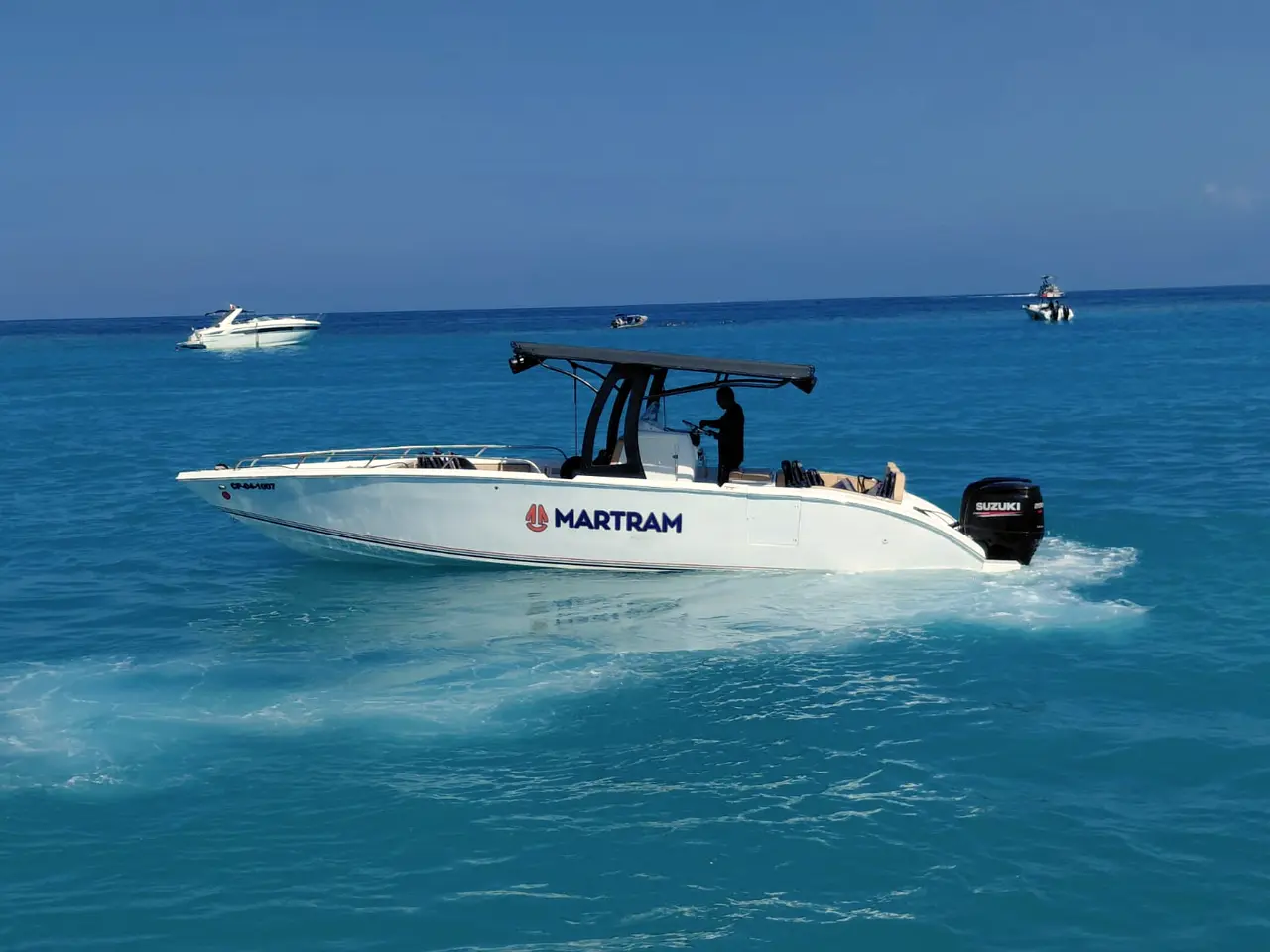 White boat with a dark canopy on turquoise water