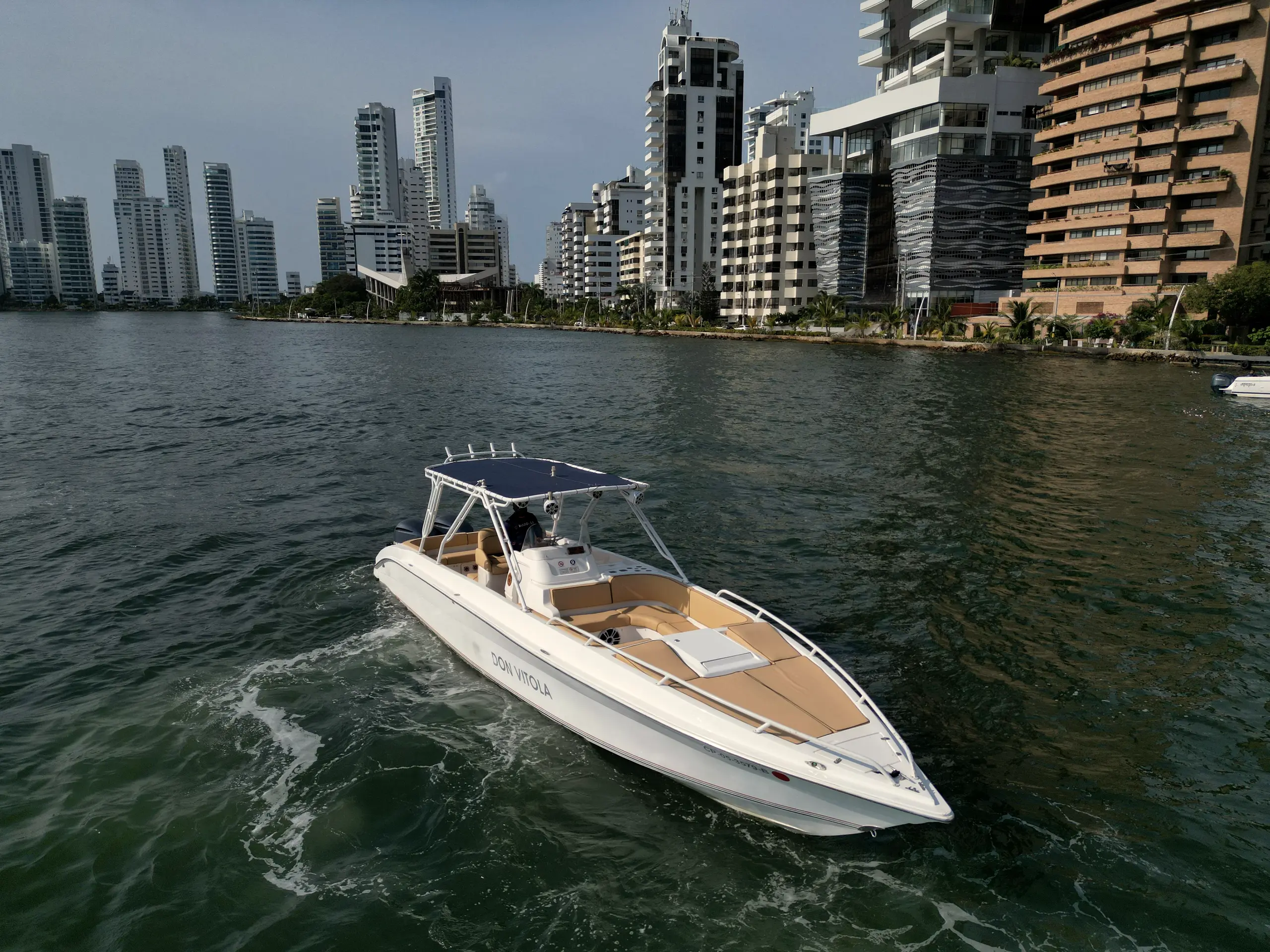 White boat cruising along a coast of high-rise buildings