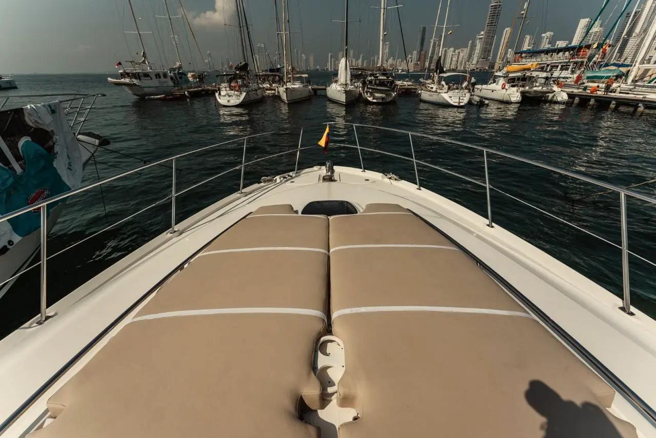 Yacht bow with sun pads facing a sailboat marina